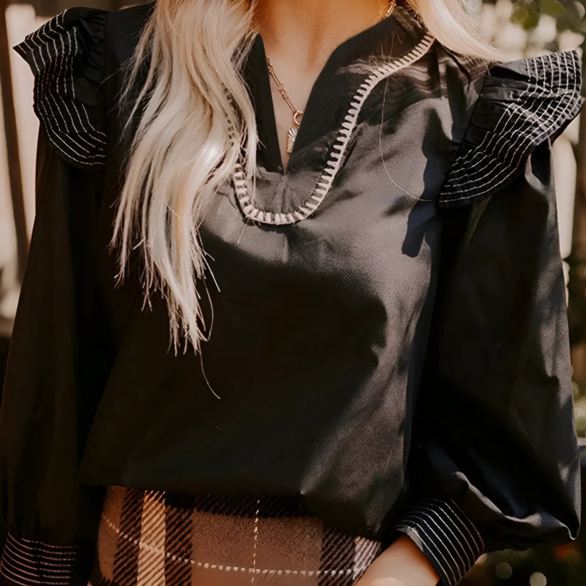 Black V-neck long sleeve blouse with ruffle trim and contrast colour stitching.