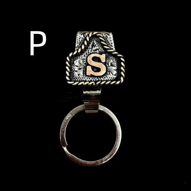 Handmade metal cow tag belt keychain showing one of 26 colour options, each marked with a different alphabet letter.