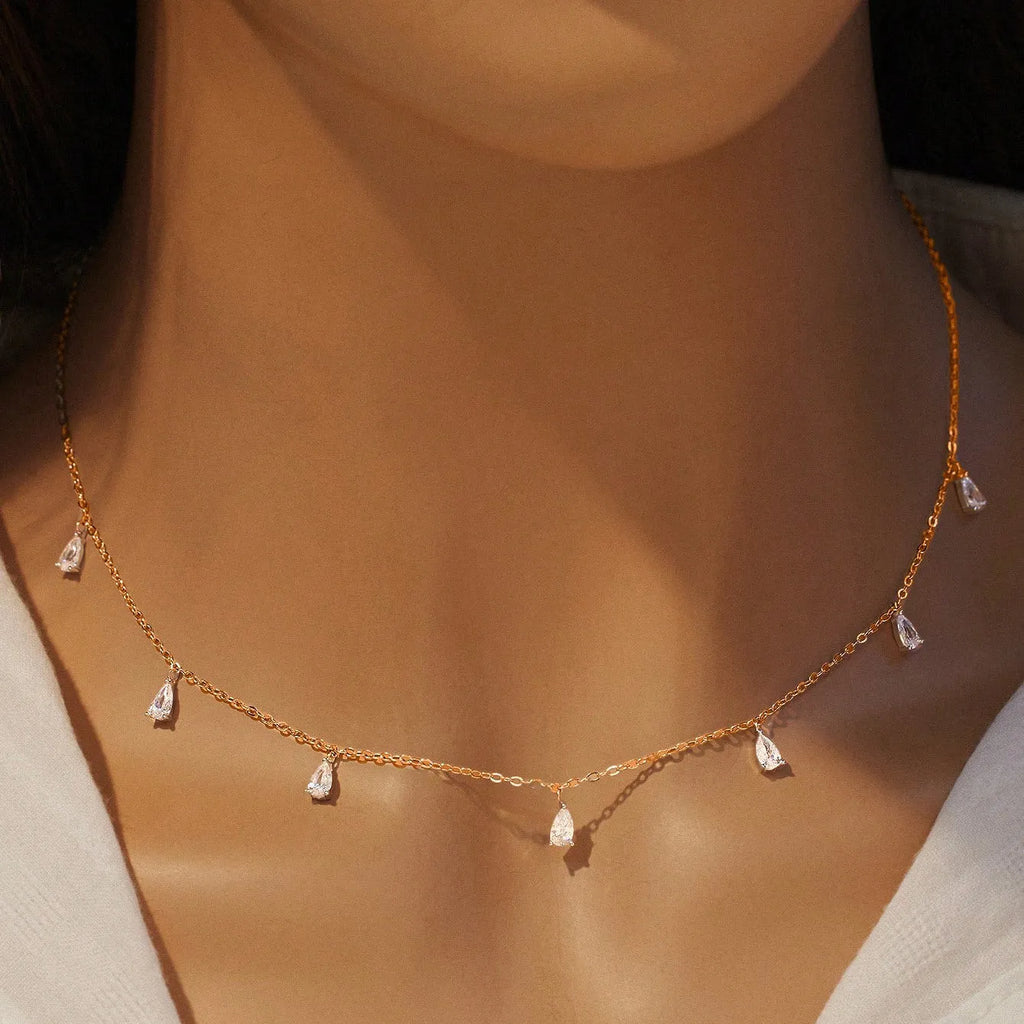 Women's silver necklace with a drop-shaped zircon pendant on an O-shaped chain, shown in golden yellow.