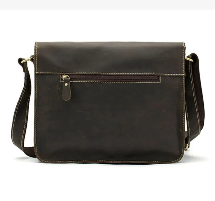 Brown full-grain leather vintage messenger bag with brass buckle, shown open to reveal padded laptop sleeve and internal pockets.