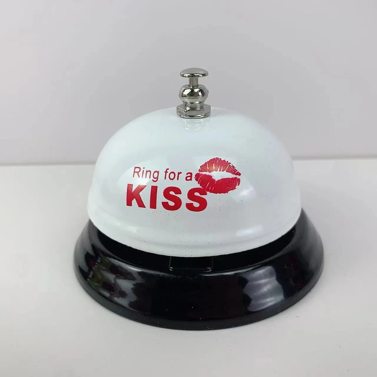 Iron table serving bell in multiple colour options on a wooden surface.