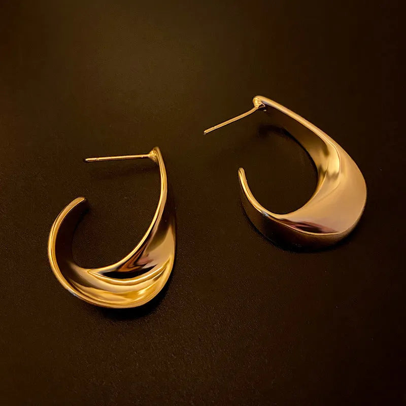 A pair of geometric round earrings with a twisted metal design in a gold electroplated finish.