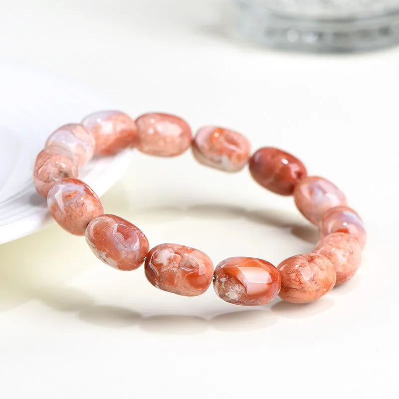 Natural cherry agate bracelet with barrel-shaped beads and a Ruyi design element on a wrist.