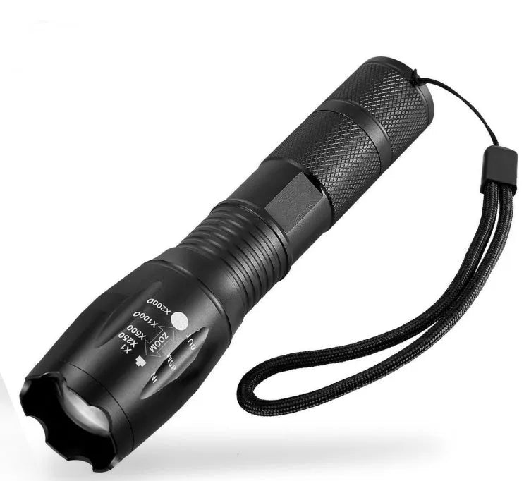 Black aluminium alloy zoomable focus LED torch with antiskid grip on a textured surface.