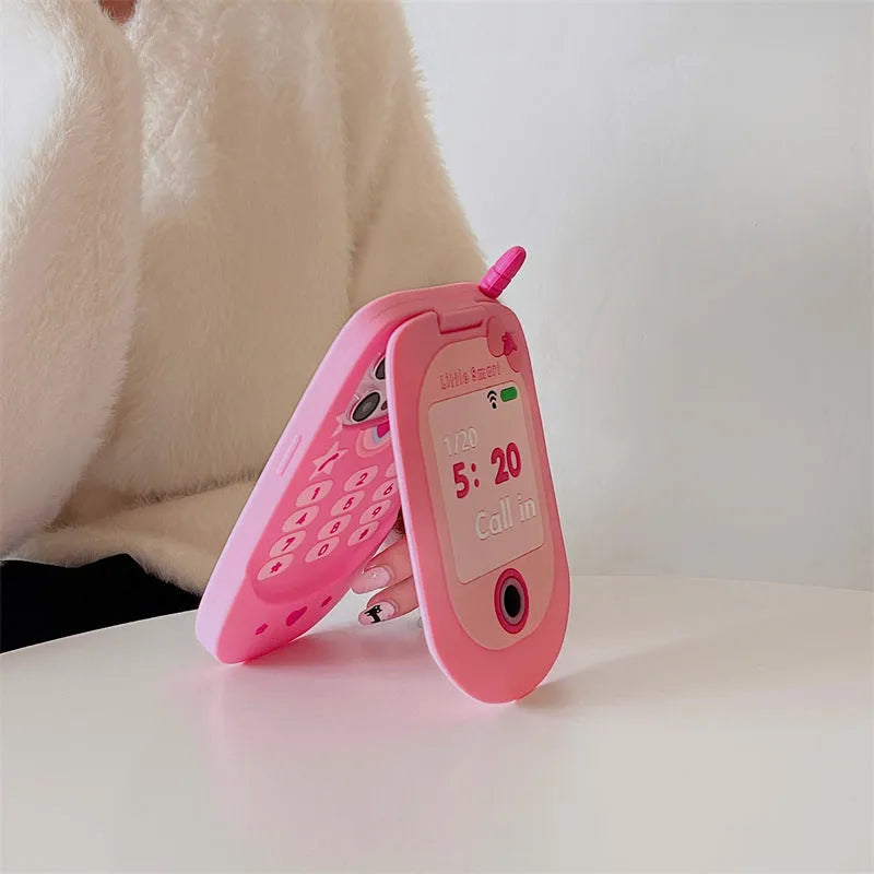Pink silicone iPhone case shaped like a flip phone with a built-in mirror on the front.