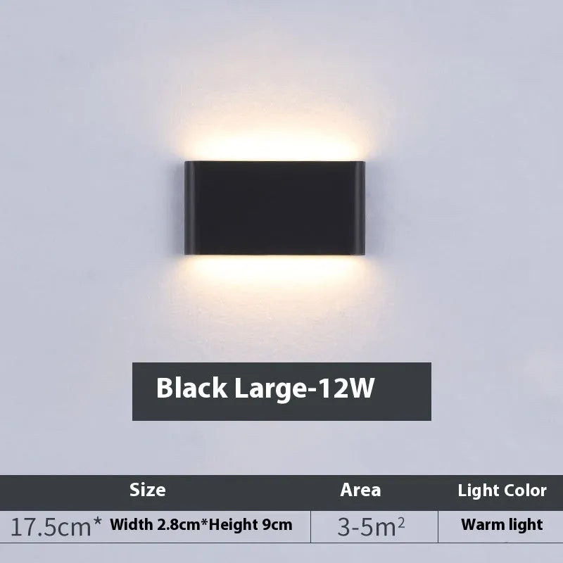 Rectangular LED outdoor wall lamp in black finish with warm light on a brick courtyard wall