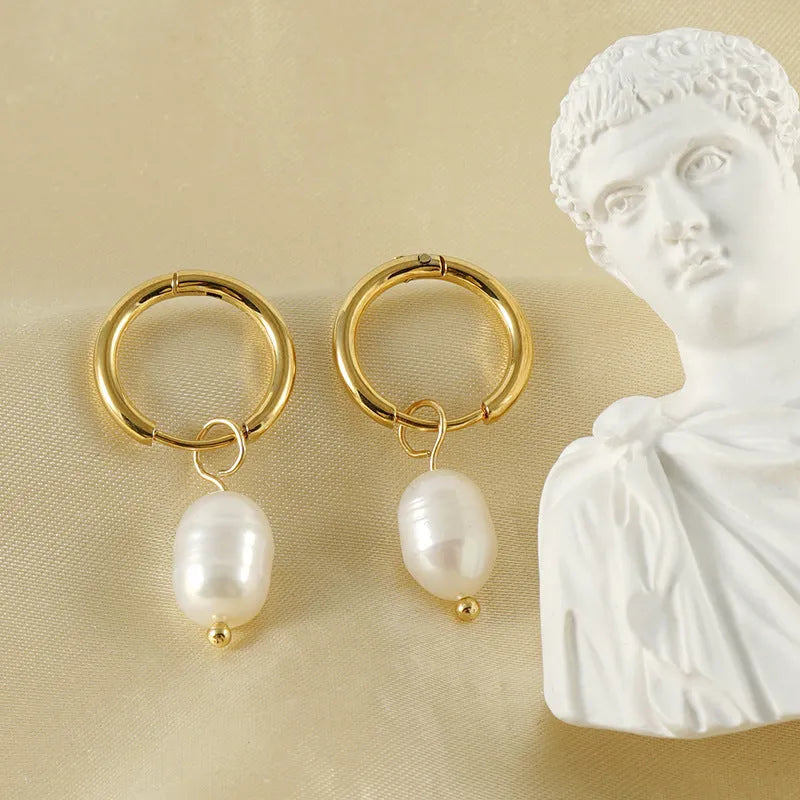 Gold geometric drop earrings with a central freshwater pearl on hypoallergenic posts.
