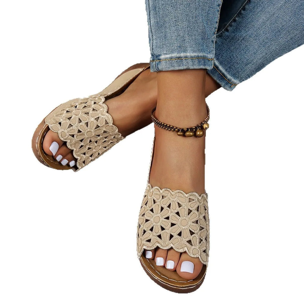 Women's black beach slippers with a flower cutout design on the upper and a wedge-style rubber sole.
