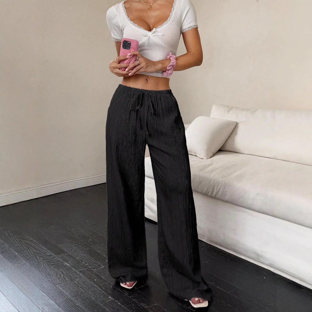 Black wide-leg women's trousers with a front lace-up waist detail on a neutral background.