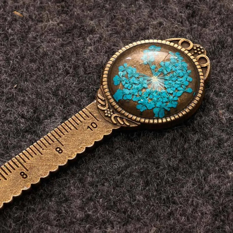Handmade dried gypsophila and clover flower bookmark ruler on a book, showing 12cm length.