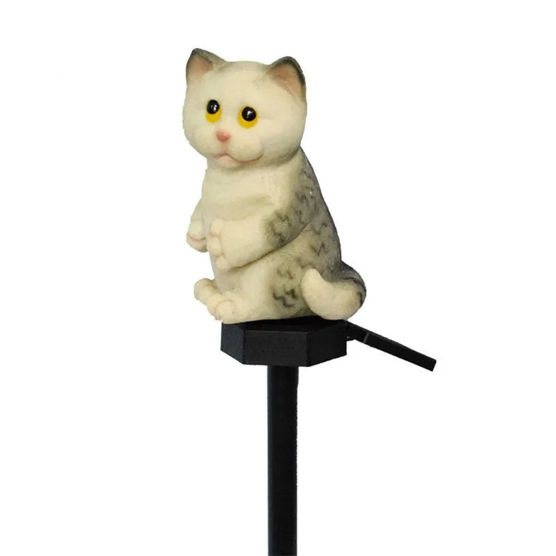 Brown resin cat-shaped solar garden light illuminating in a evening garden setting.