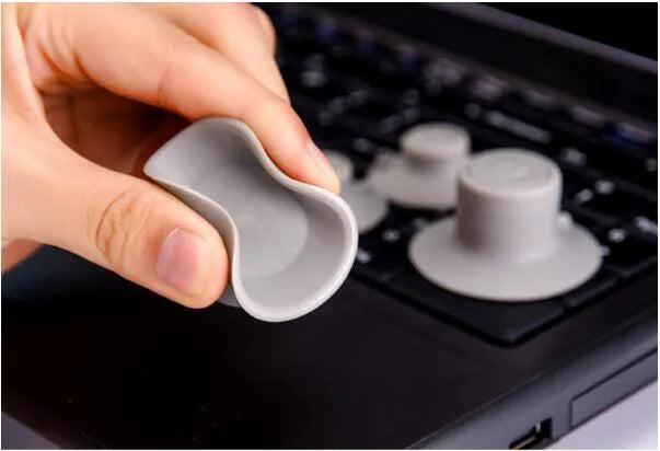 Grey laptop cooling stand with four silicone feet creating an air gap under a silver laptop.