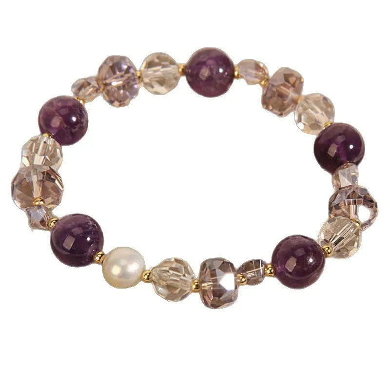 Women's artificial amethyst bracelet with four-leaf clover charm and pearl accents on a wrist.