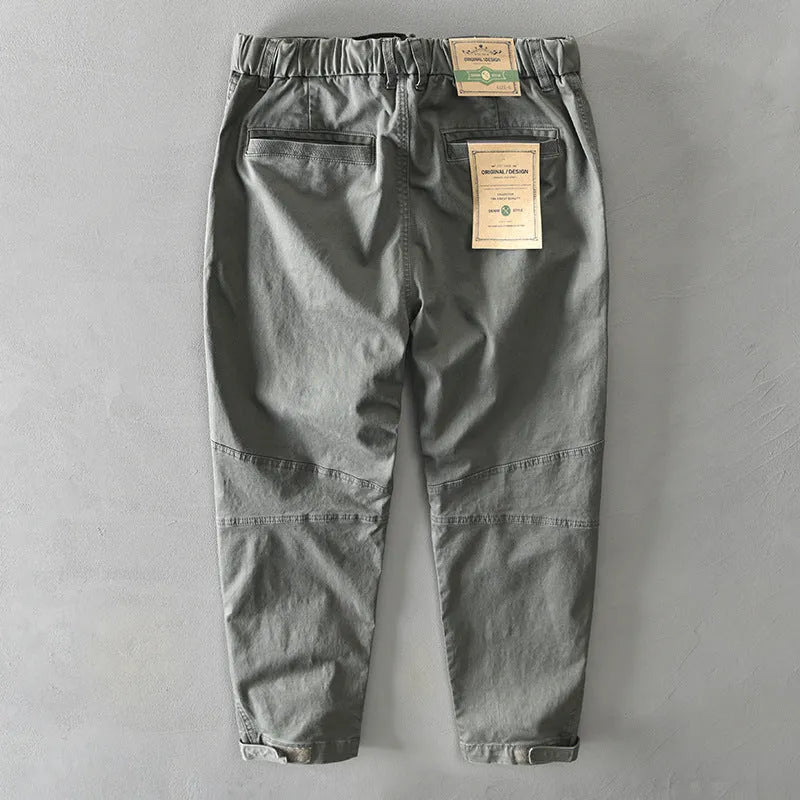 Man wearing khaki coloured casual cotton overalls with an elastic mid-waist and loose trouser legs.