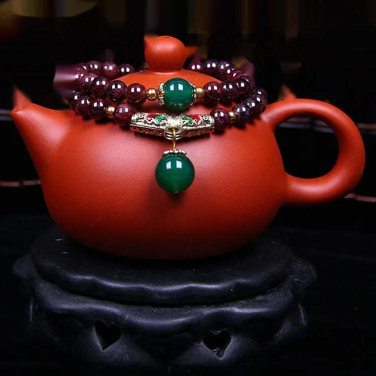 Natural red garnet 7mm bracelet with a golden toad charm on wrist, showing double ring clasp.