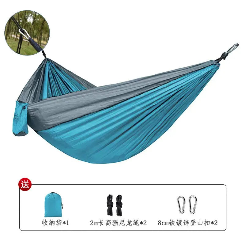Blue nylon parachute camping hammock hung between two trees, showing its full 270cm length and 140cm width.