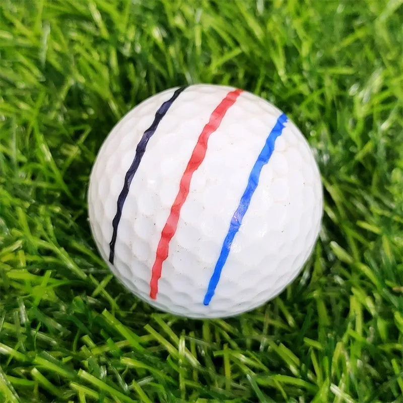 Close-up of a white golf ball with a black etched line next to a plastic golf scriber alignment tool with multiple tips.
