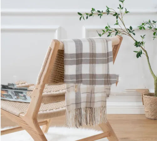 Acrylic chenille plaid throw blanket with tassel trim in gray and white geometric pattern on sofa
