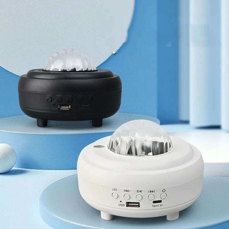 White and black galaxy star projector night light with Bluetooth speaker on a surface.