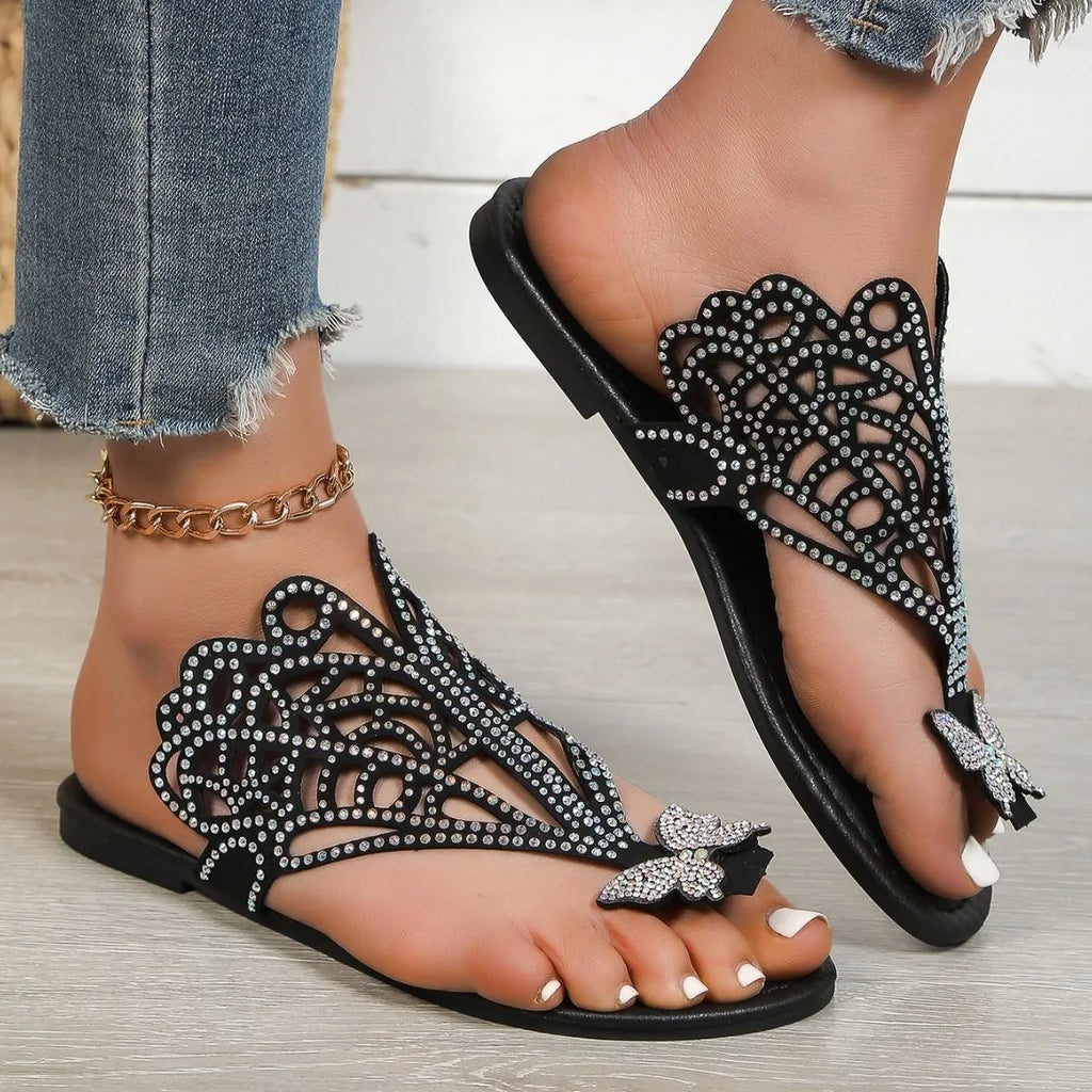 Black women's flat-heeled slip-on sandals with a flip-toe design and rhinestone decoration.