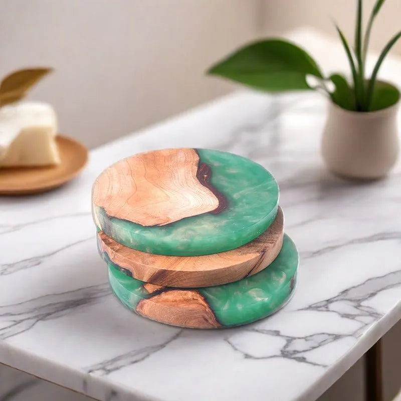 Round and square black and green resin coasters with wood texture for tea pots on a table.
