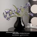 Modern round belly ceramic vase with coloured glaze, shown in black and white, some with artificial flowers.