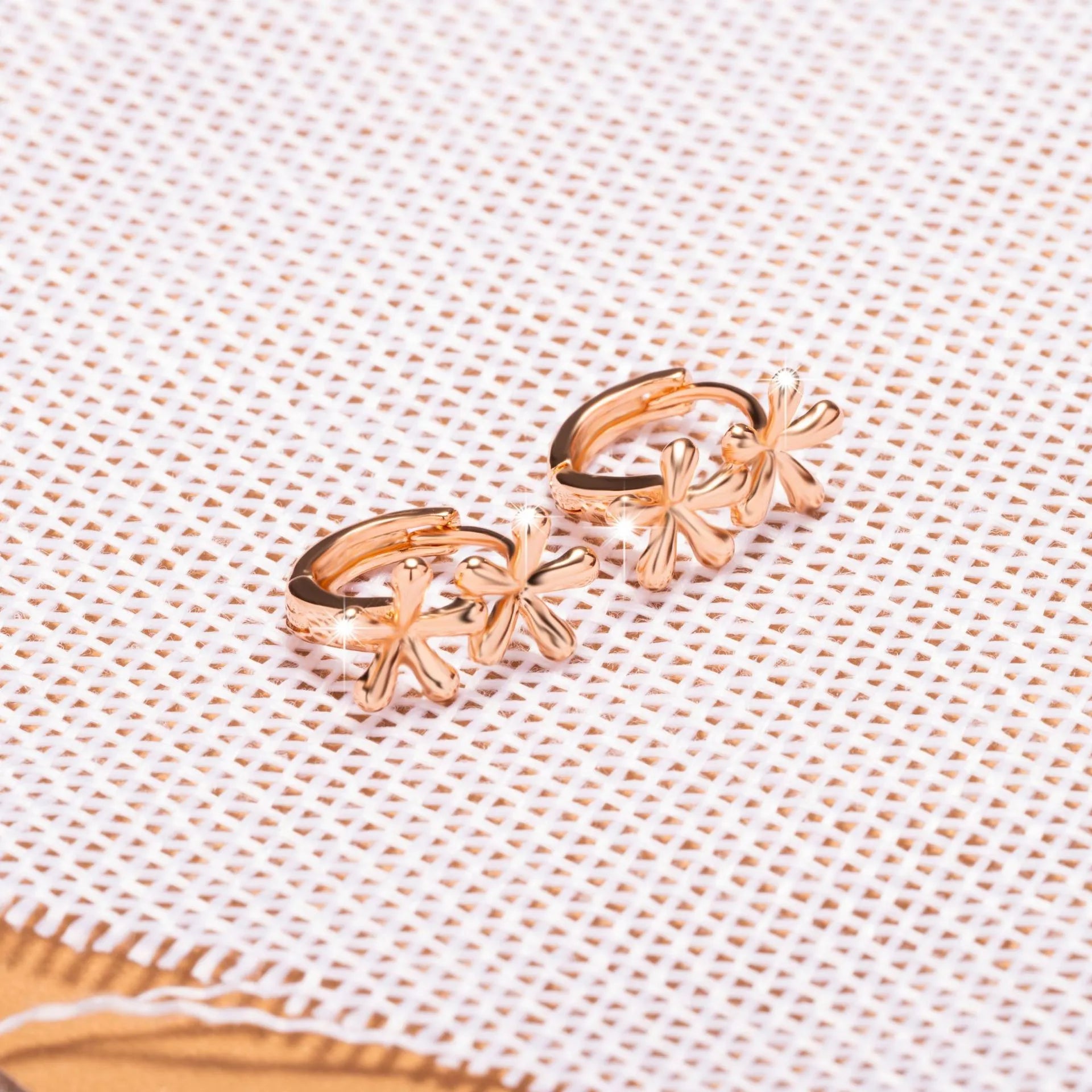 Rose gold waterdrop flower stud earrings with circular floral design on a white background.