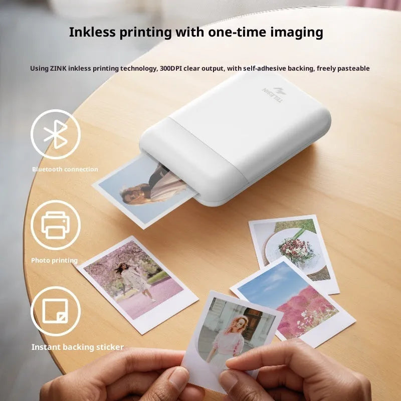 Pocket photo printer in plastic casing with carry-on bag and photo paper on table
