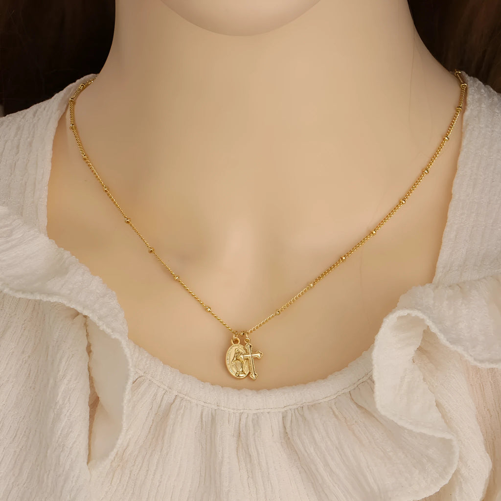 Geometric Virgin Mary cross pendant on a 45cm gold-coloured chain with an adjustable lobster clasp.