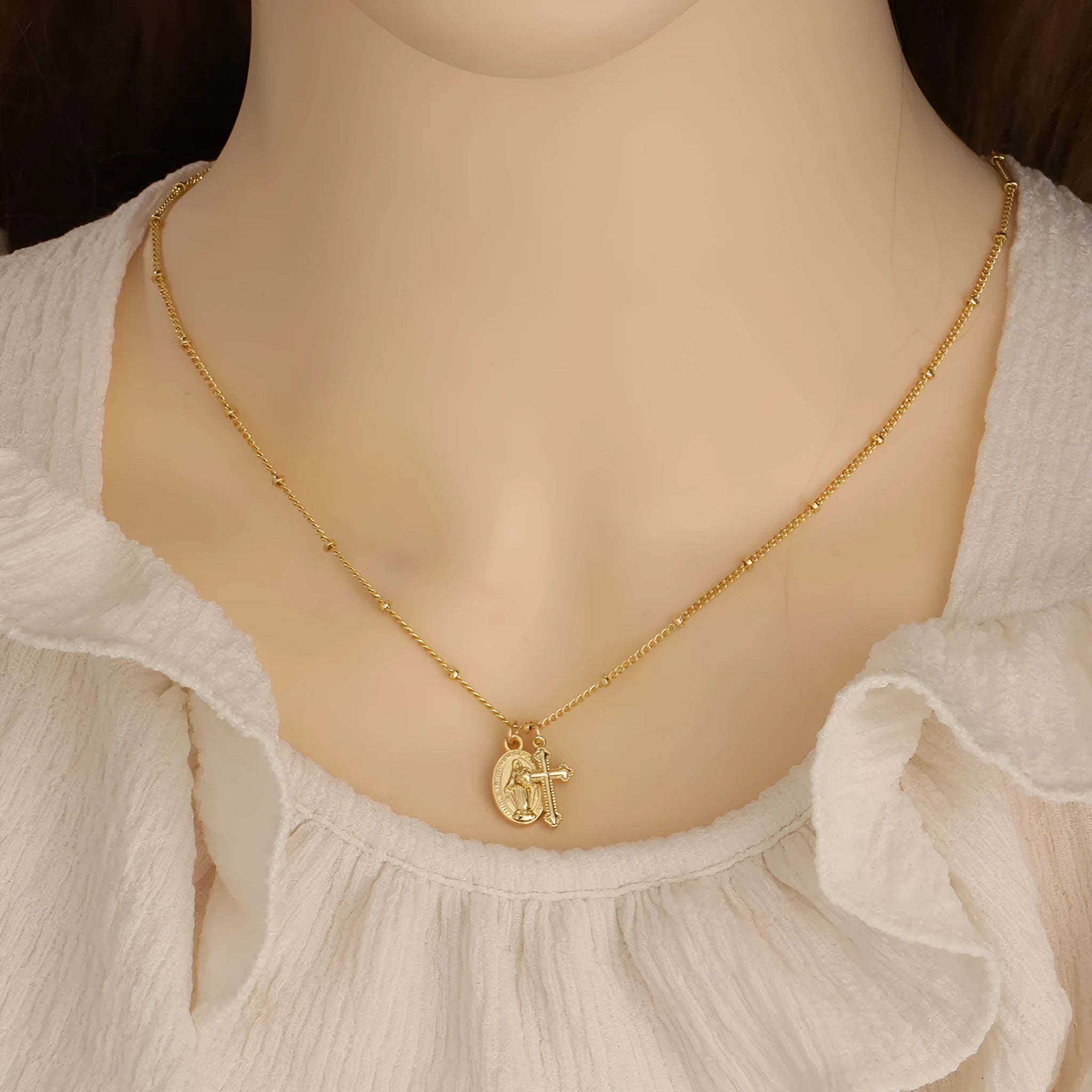Geometric Virgin Mary cross pendant on a 45cm gold-coloured chain with an adjustable lobster clasp.