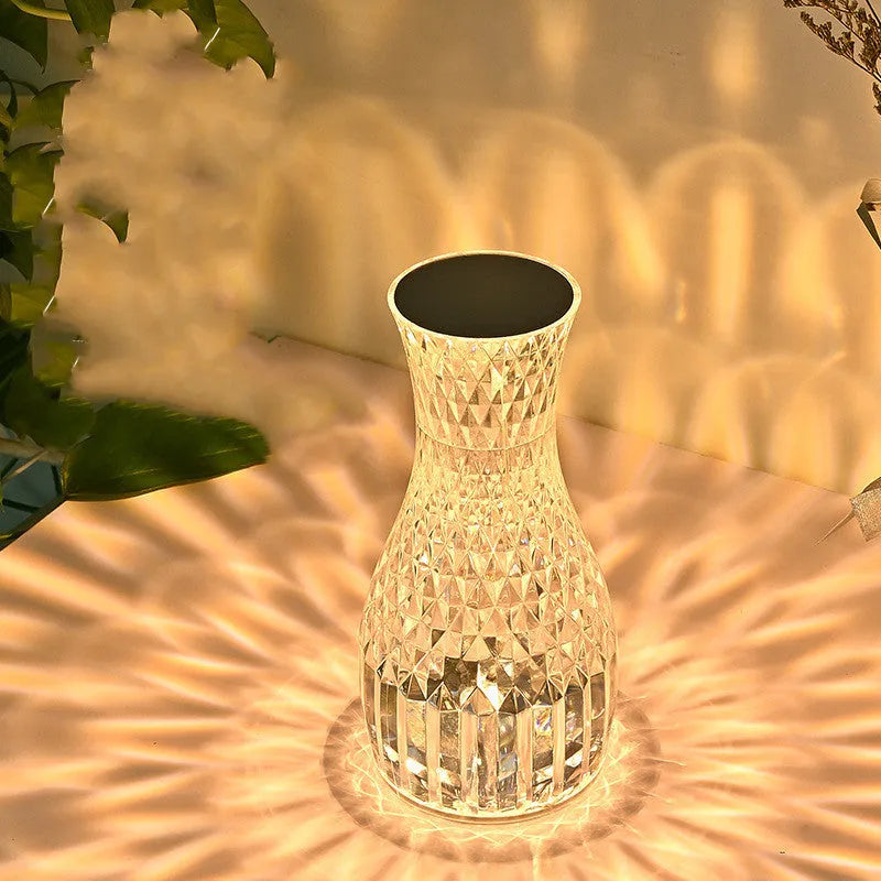 Vase-shaped crystal table lamp with LED lights and remote control on a bedside table
