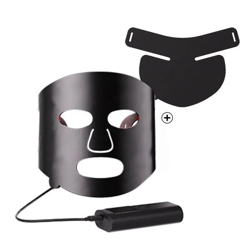 Black and white LED phototherapy face mask with controller and strap on a table.