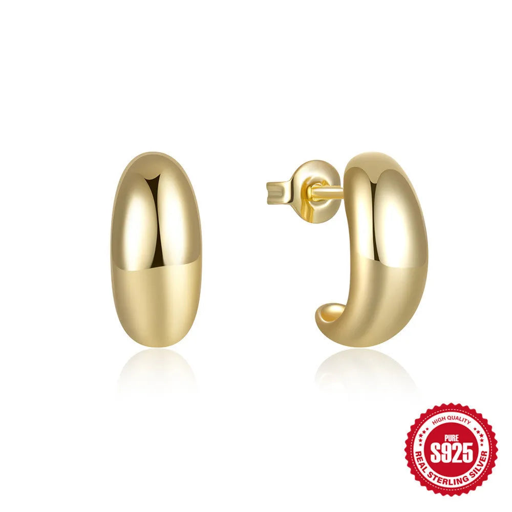 Close-up of a glossy C-shaped sterling silver stud earring in a gold electroplated finish.