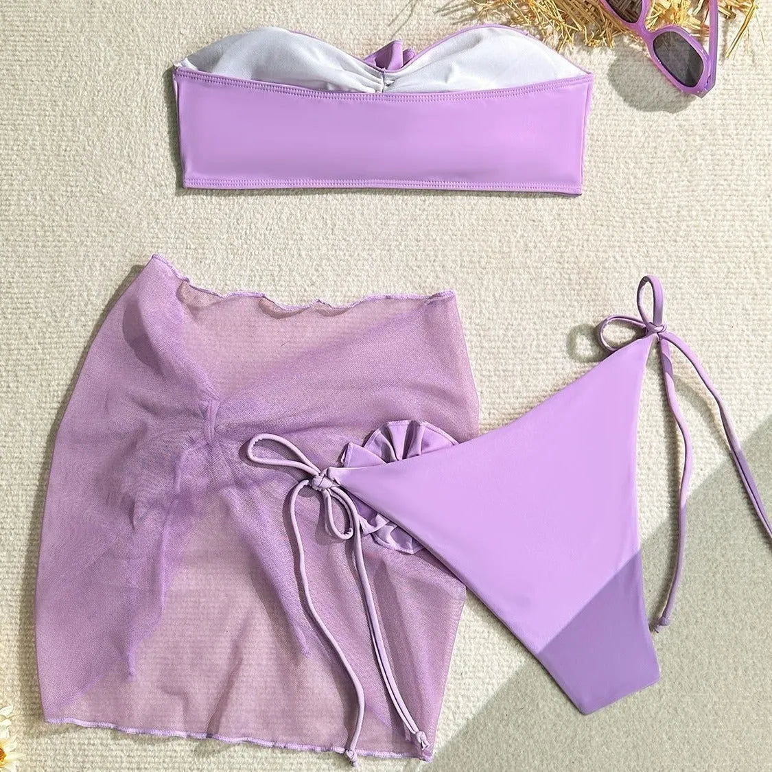 Women's pink swimsuit set with 3D flower tube top, high-waisted bottoms, and separate tie-front skirt laid flat.