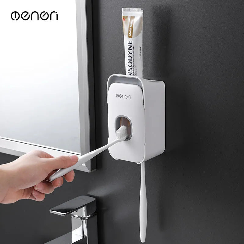 Automatic toothpaste dispenser in grey, blue, and pink colours on a bathroom countertop.