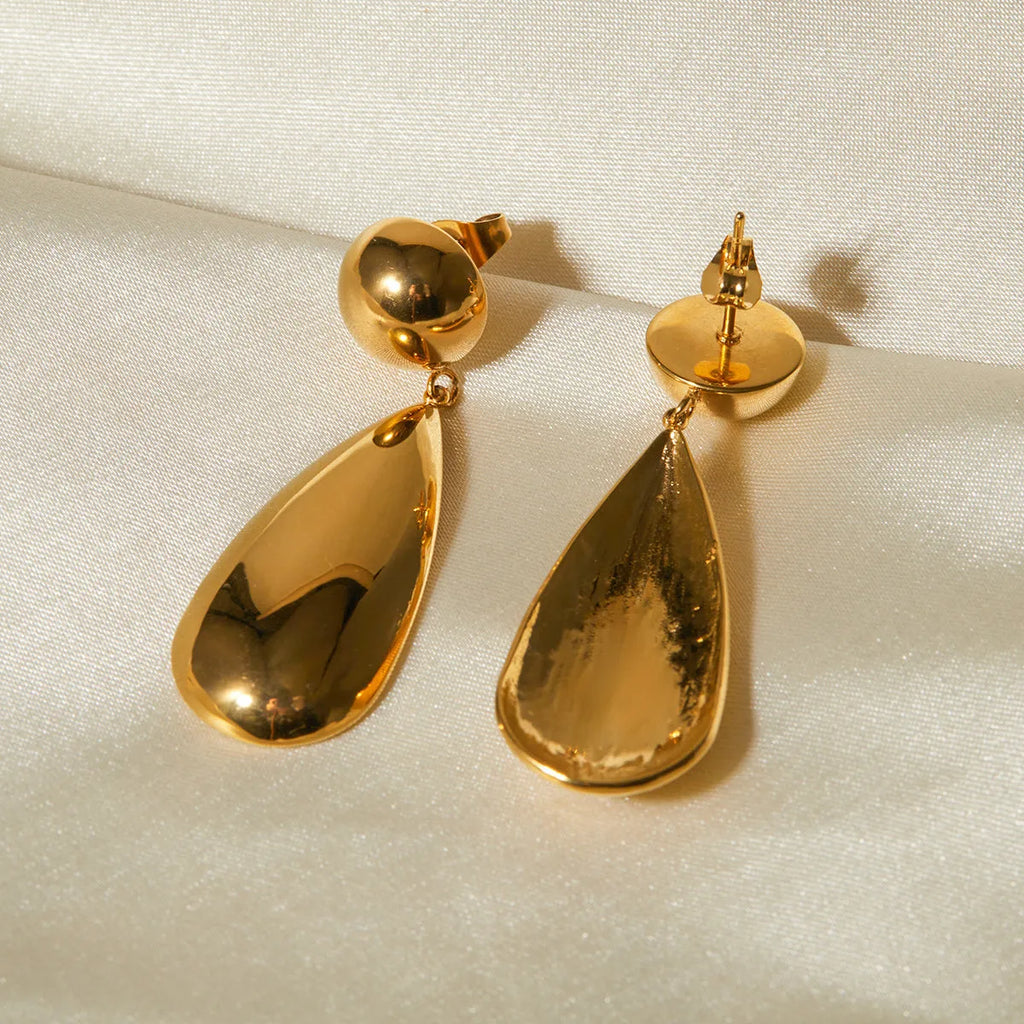 A pair of gold geometric hemisphere earrings with a water droplet pendant design on a white background.
