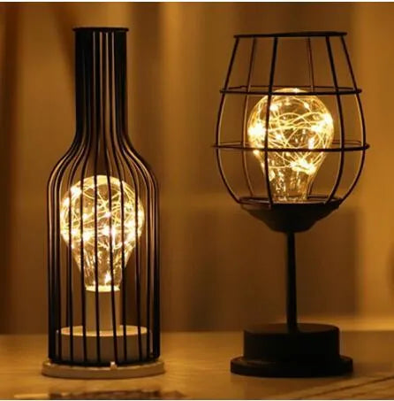 Minimalist hollow wrought iron table lamp in red wine bottle design with warm white LED light.