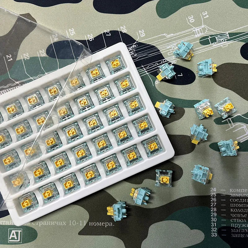 36 Sea Salt Lemon coloured mechanical keyboard switches with 3-pin connectors laid out on a table.