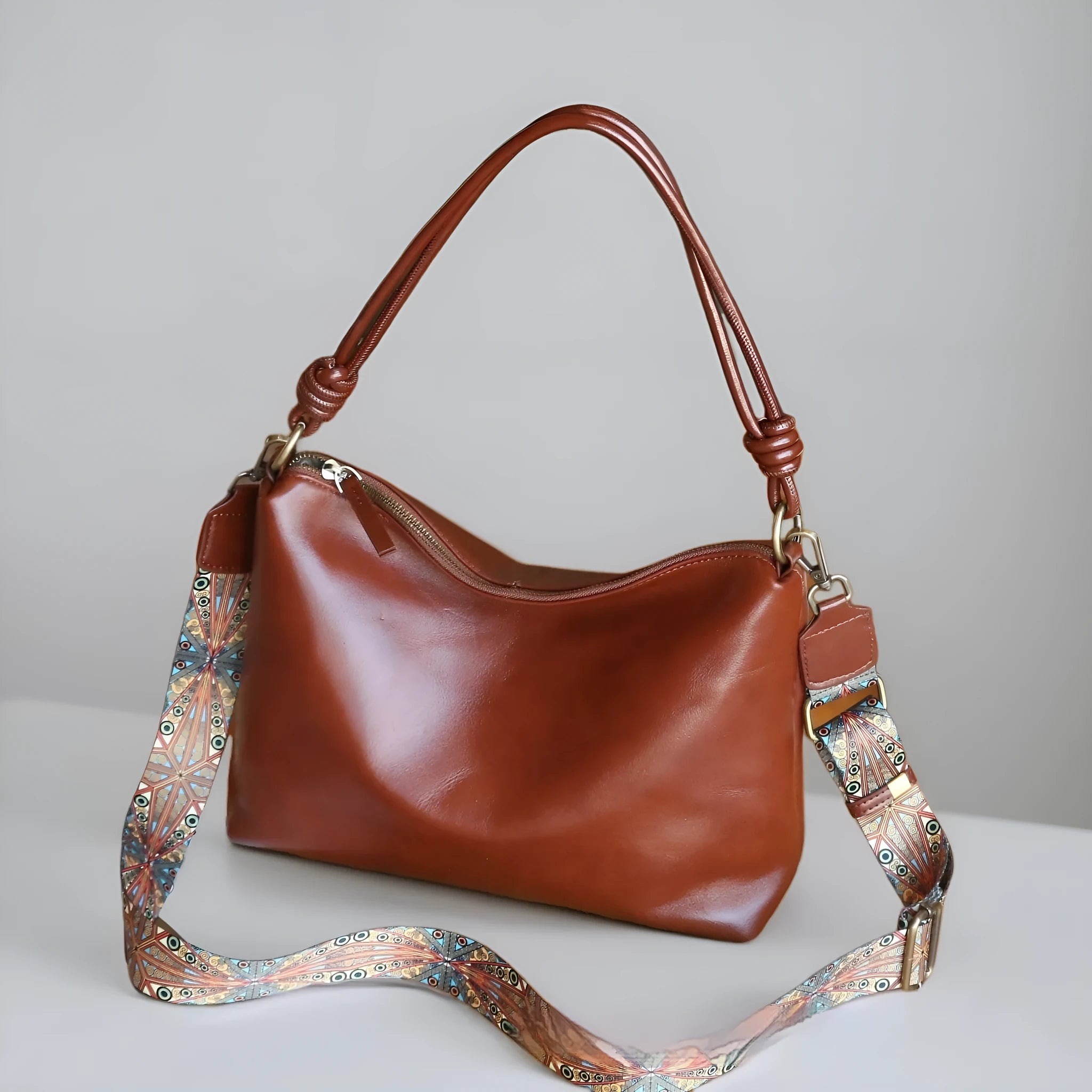 Genuine leather pillow-shaped commuter bag in caramel colour with double straps and patchwork detailing, 31x11x24cm