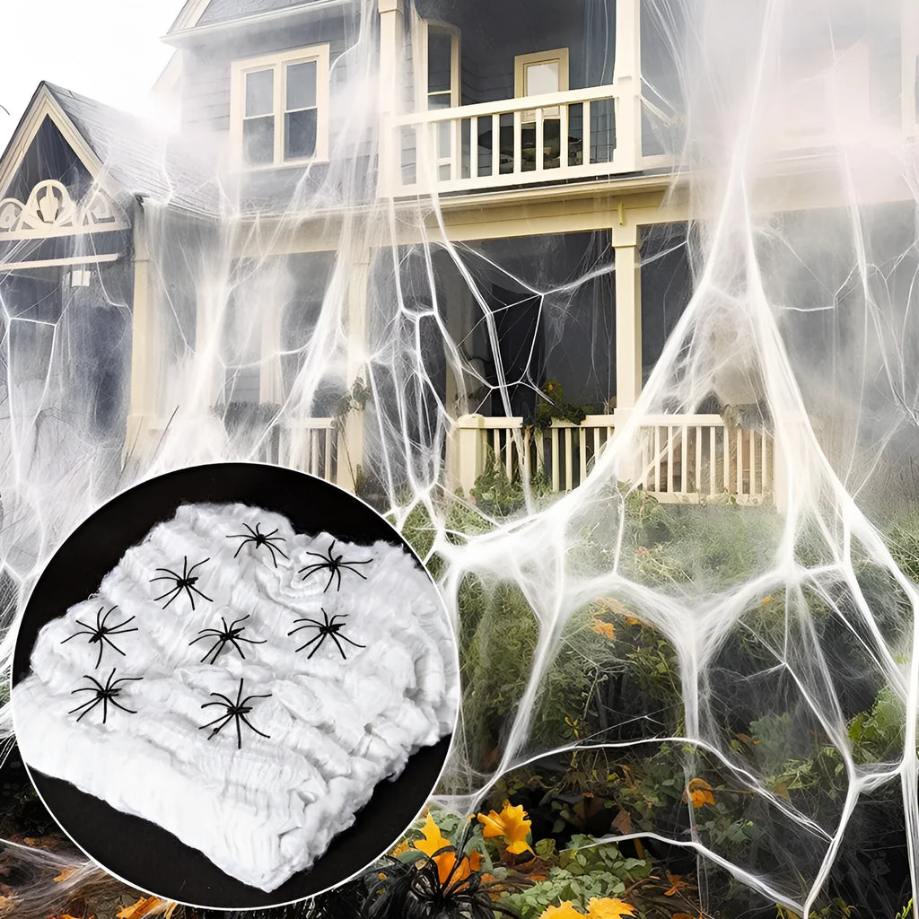 White cotton Halloween spider web decoration draped on a surface with scattered plastic spiders.