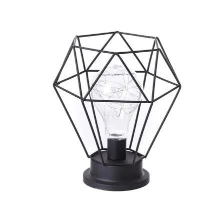 Minimalist hollow iron table lamp with warm white light on a wooden desk