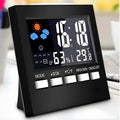 Black multifunctional perpetual calendar clock with alarm, weather forecast, thermometer, and blue backlight on a desk