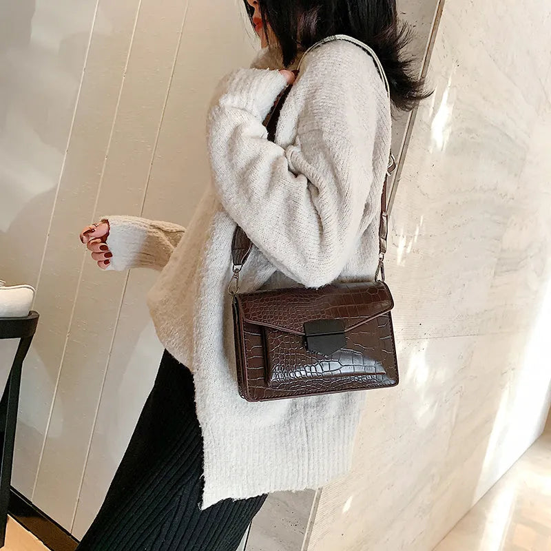 Vintage style black crossbody bag with an adjustable shoulder strap on a mannequin.