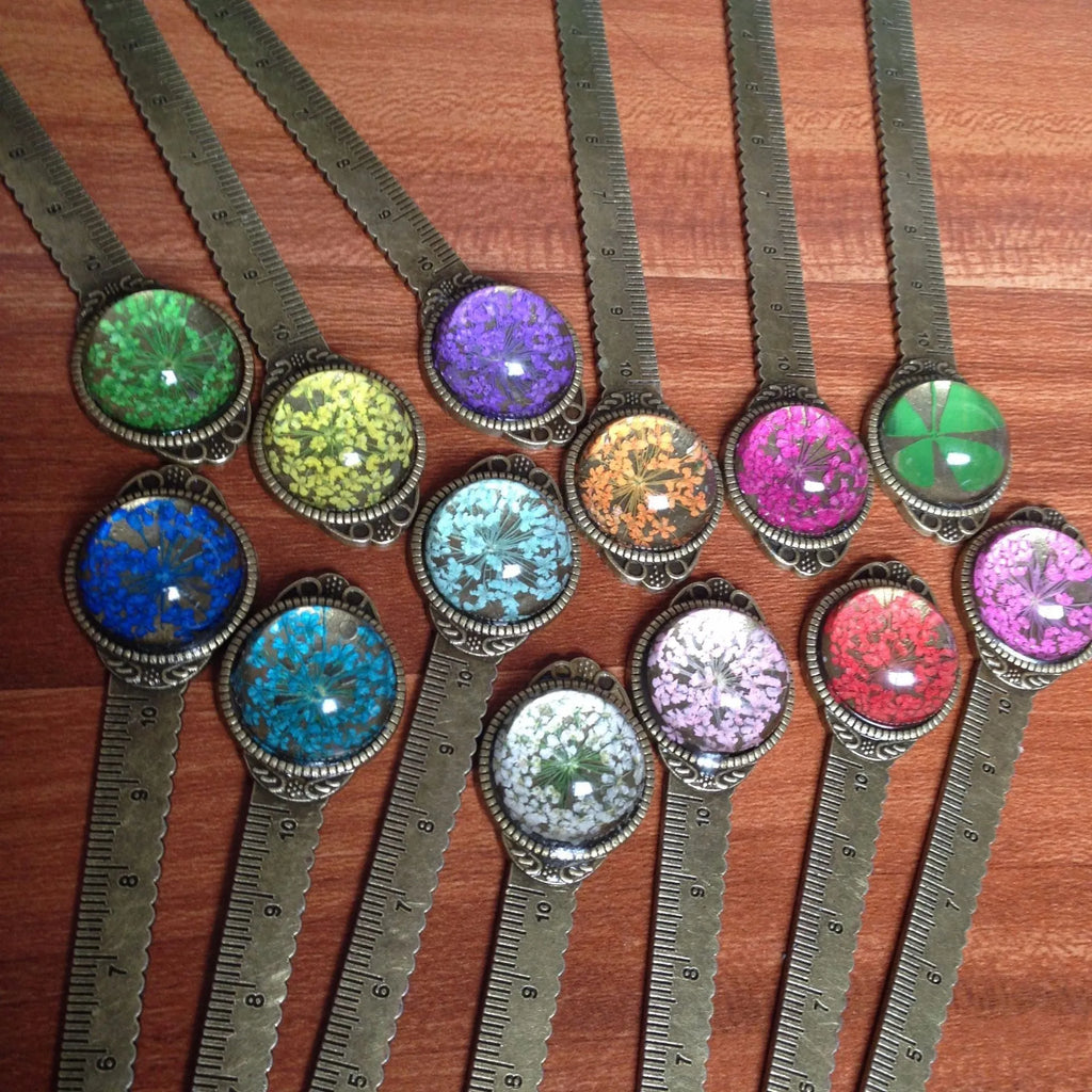 Handmade dried gypsophila and clover flower bookmark ruler on a book, showing 12cm length.