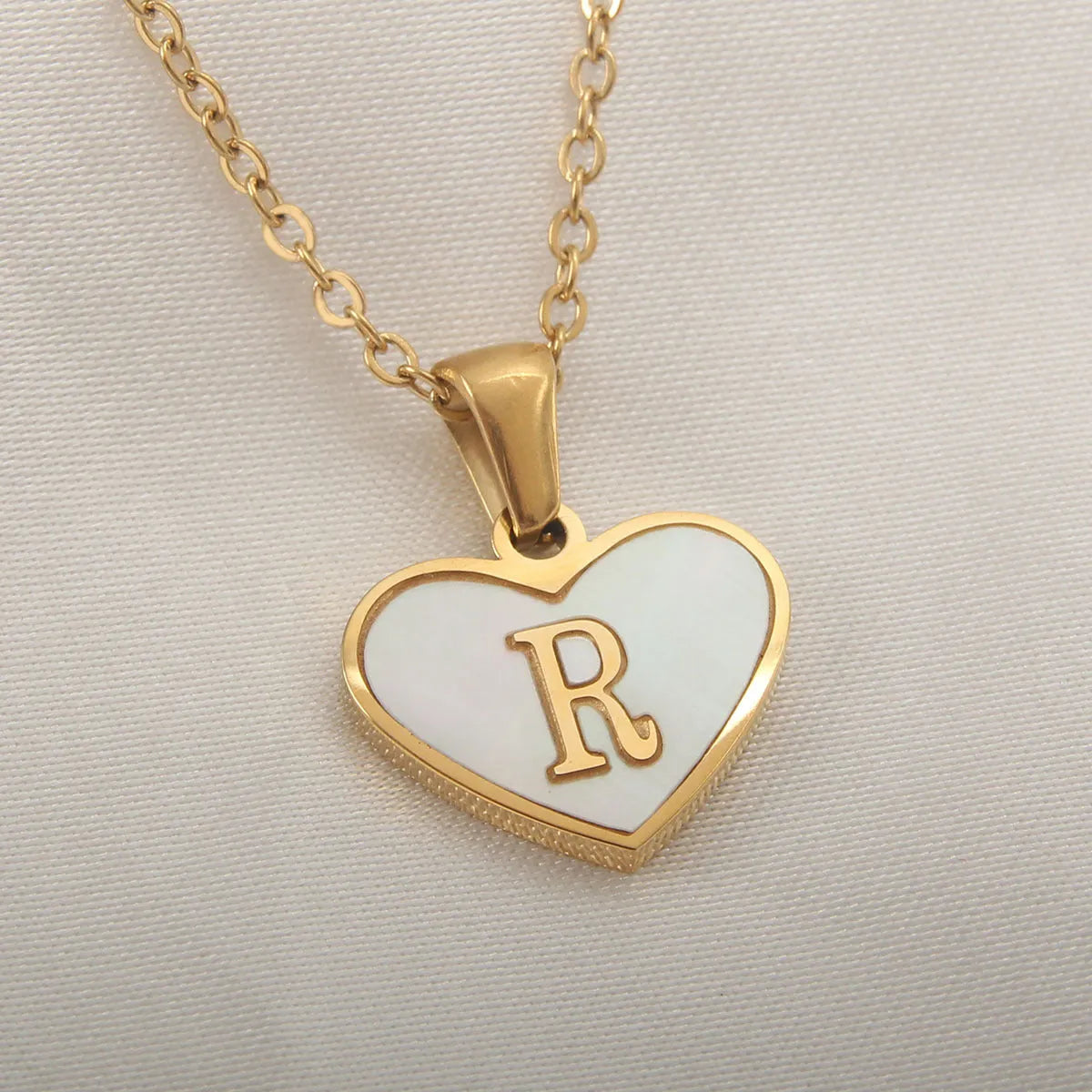 Gold-plated heart necklace with white shell pendant showing initial engraving on stainless steel chain