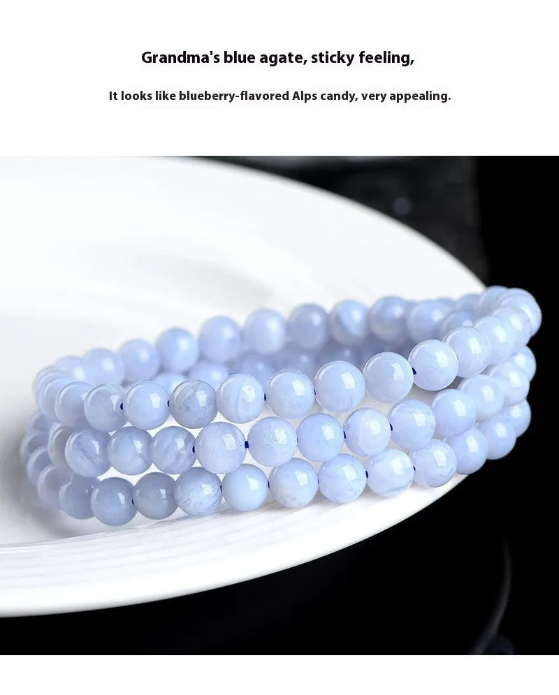 Close-up of a handmade blue agate bracelet with natural striped beads on a wrist.