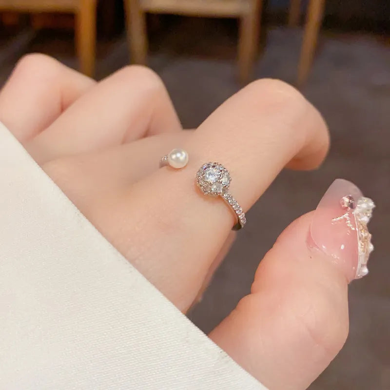 Gold or silver coloured open-end ring with a round zircon pearl on a geometric band.