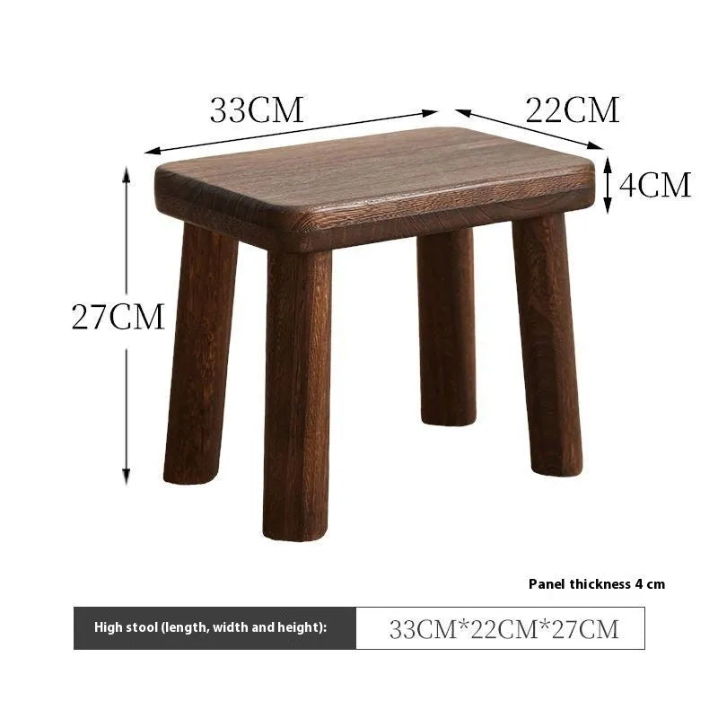 Solid wooden shoe changing stool with a distressed finish, shown in a living room setting.