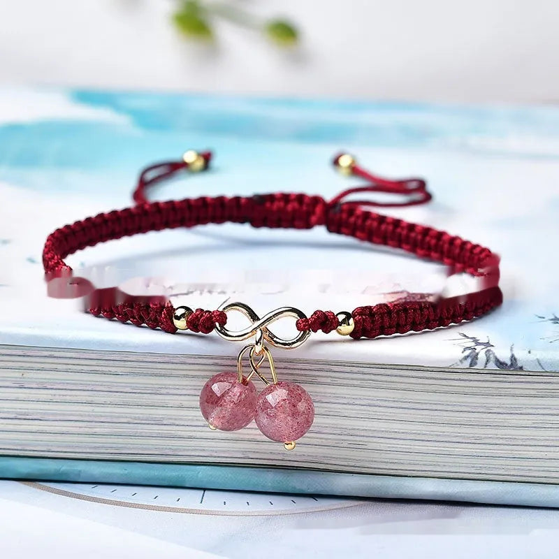 Close-up of a women's natural crystal bracelet with a detailed cherry charm in strawberry quartz colour.