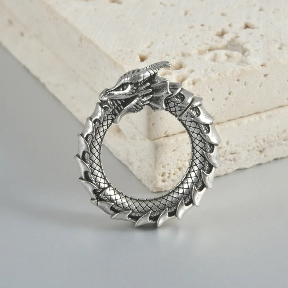 Pair of antique silver dragon-shaped geometric earrings with hollow-out design on a plain background.
